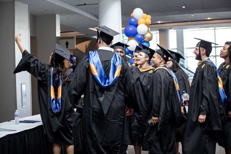 A group of graduates in regalia poses together for a selfie at Goizueta Commencement 2024